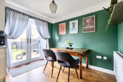 Dining area with table and chairs near french doors with curtains and green wall.