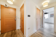 Hallway with wooden entrance door and view towards living area.