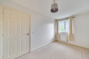 Empty bedroom with carpeted floor, light walls, and window with curtains.