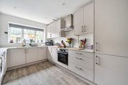 Kitchen with white cabinets, integrated oven and window above the sink.