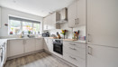 Kitchen with white cabinets, integrated oven and window above the sink.