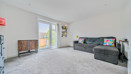 Spacious living room with grey carpet, large window, radiator, and corner sofa.
