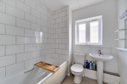Bathroom with tiled walls, wash basin, toilet and window.