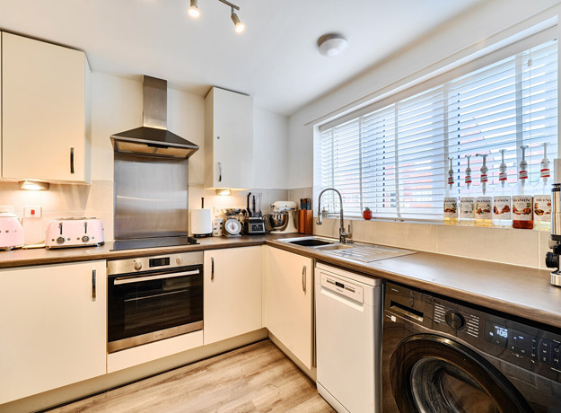 Modern fitted kitchen with integrated oven, hob, sink and worktops.