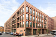 Brick apartment building with multiple balconies and large windows.