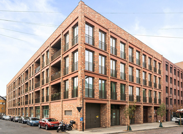 Brick apartment building with multiple balconies and large windows.
