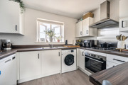 White kitchen with appliances, wood-effect worktops, and window above the sink.