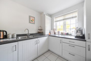 Kitchen with white cabinets, black worktops, sink and window.
