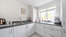 Kitchen with white cabinets, black worktops, sink and window.