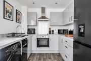 White fitted kitchen with appliances, integrated oven and hob, and worktops.