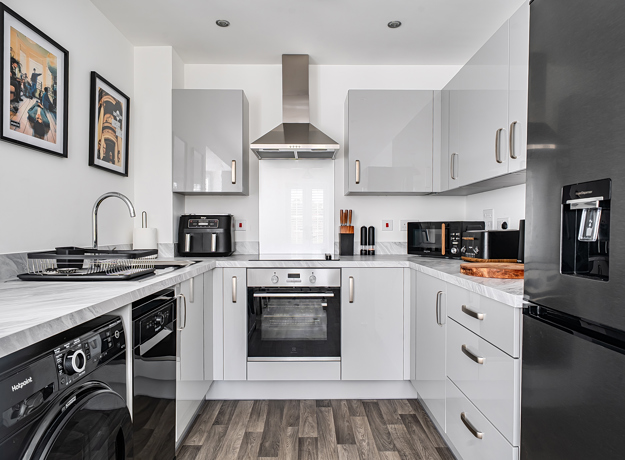 White fitted kitchen with appliances, integrated oven and hob, and worktops.