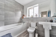 Bathroom with a bath, toilet, pedestal sink and wall mirror.