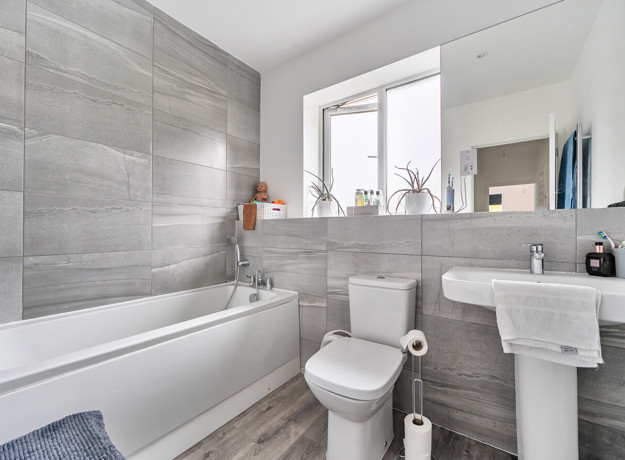 Bathroom with a bath, toilet, pedestal sink and wall mirror.
