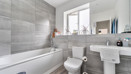 Bathroom with a bath, toilet, pedestal sink and wall mirror.