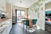 Kitchen and dining area with table, chairs, wall mural and patio doors.