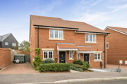 Semi-detached red brick house with driveway, small front garden and hedges.