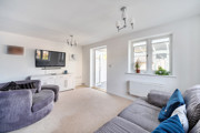 Bright living room with grey sofas, beige carpet, large window and French doors leading to conservatory.