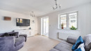 Bright living room with grey sofas, beige carpet, large window and French doors leading to conservatory.