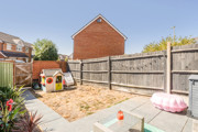 Enclosed garden with paved patio, fencing and playhouse.