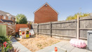 Enclosed garden with paved patio, fencing and playhouse.