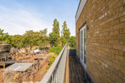 Side view from the balcony showing a brick wall and surrounding trees.