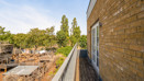 Side view from the balcony showing a brick wall and surrounding trees.