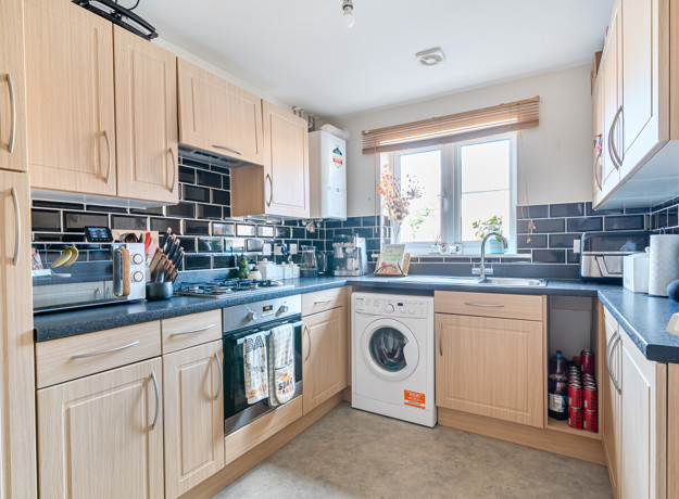 Kitchen with fitted units, worktops, washing machine and window.