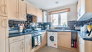Kitchen with fitted units, worktops, washing machine and window.