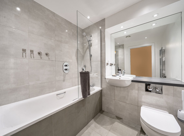 Bathroom with bath, shower, sink, toilet and wall mirror.