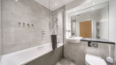 Bathroom with bath, shower, sink, toilet and wall mirror.