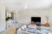 Living and dining area with sofas and TV, leading into kitchen.