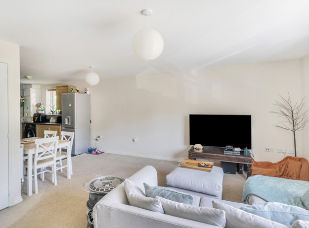 Living and dining area with sofas and TV, leading into kitchen.