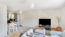 Living and dining area with sofas and TV, leading into kitchen.