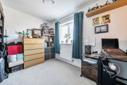 Bedroom with desk, drawers, shelving and window with curtains.