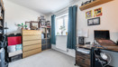 Bedroom with desk, drawers, shelving and window with curtains.
