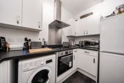 Kitchen with white cabinets, appliances, and dark worktops