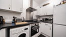 Kitchen with white cabinets, appliances, and dark worktops