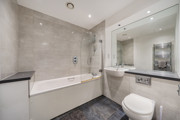 Bathroom with bath, shower screen, vanity unit, mirror and toilet.