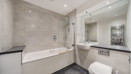 Bathroom with bath, shower screen, vanity unit, mirror and toilet.
