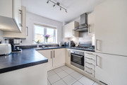 Fitted kitchen with integrated oven, hob, worktops and window.
