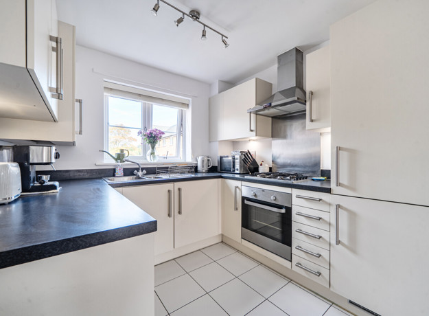 Fitted kitchen with integrated oven, hob, worktops and window.