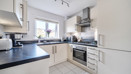 Fitted kitchen with integrated oven, hob, worktops and window.