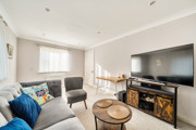 Living room with sofas, television unit, coffee table and windows.