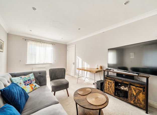 Living room with sofas, television unit, coffee table and windows.
