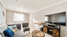 Living room with sofas, television unit, coffee table and windows.