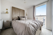 Bedroom with double bed, bedside tables and floor-to-ceiling window with city views.
