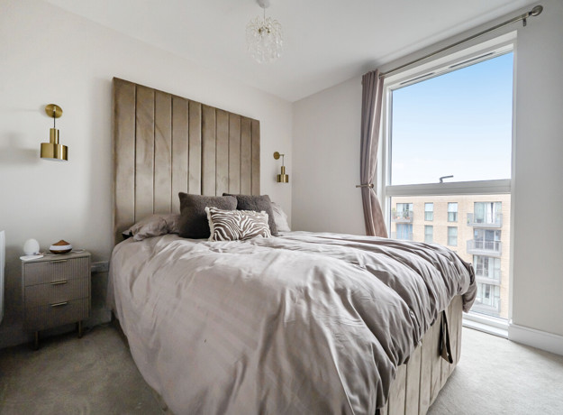 Bedroom with double bed, bedside tables and floor-to-ceiling window with city views.