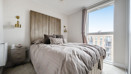 Bedroom with double bed, bedside tables and floor-to-ceiling window with city views.