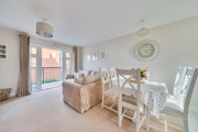 Open-plan living and dining area with table, chairs and balcony doors.