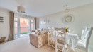 Open-plan living and dining area with table, chairs and balcony doors.